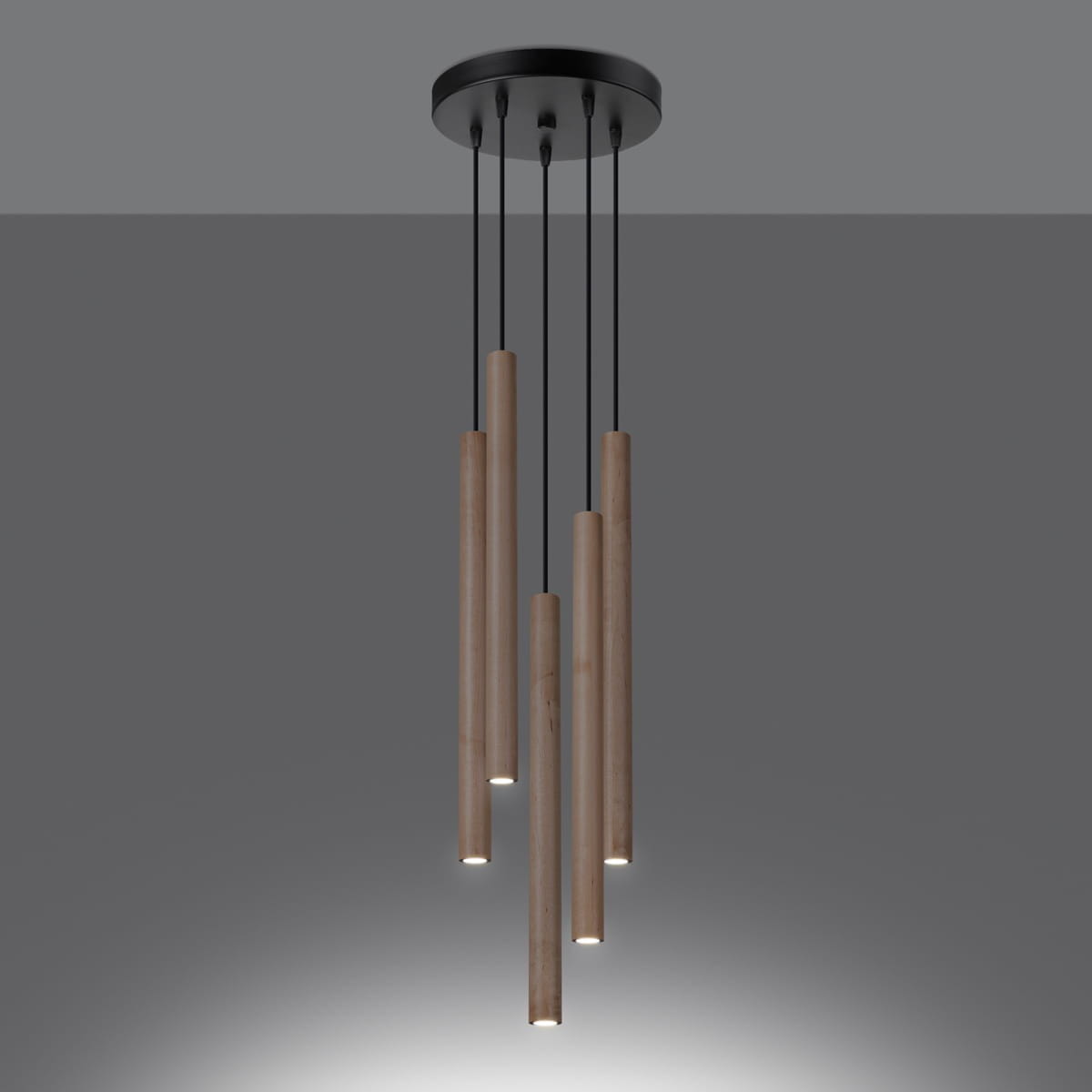 Lampa wisząca Pastelo 5xG9 w kolorze czarnym z drewnianymi, cylindrycznymi elementami. Pięć wiszących tub z oświetleniem LED, zawieszonych na cienkich przewodach, montowanych na okrągłej, czarnej podsufitce.