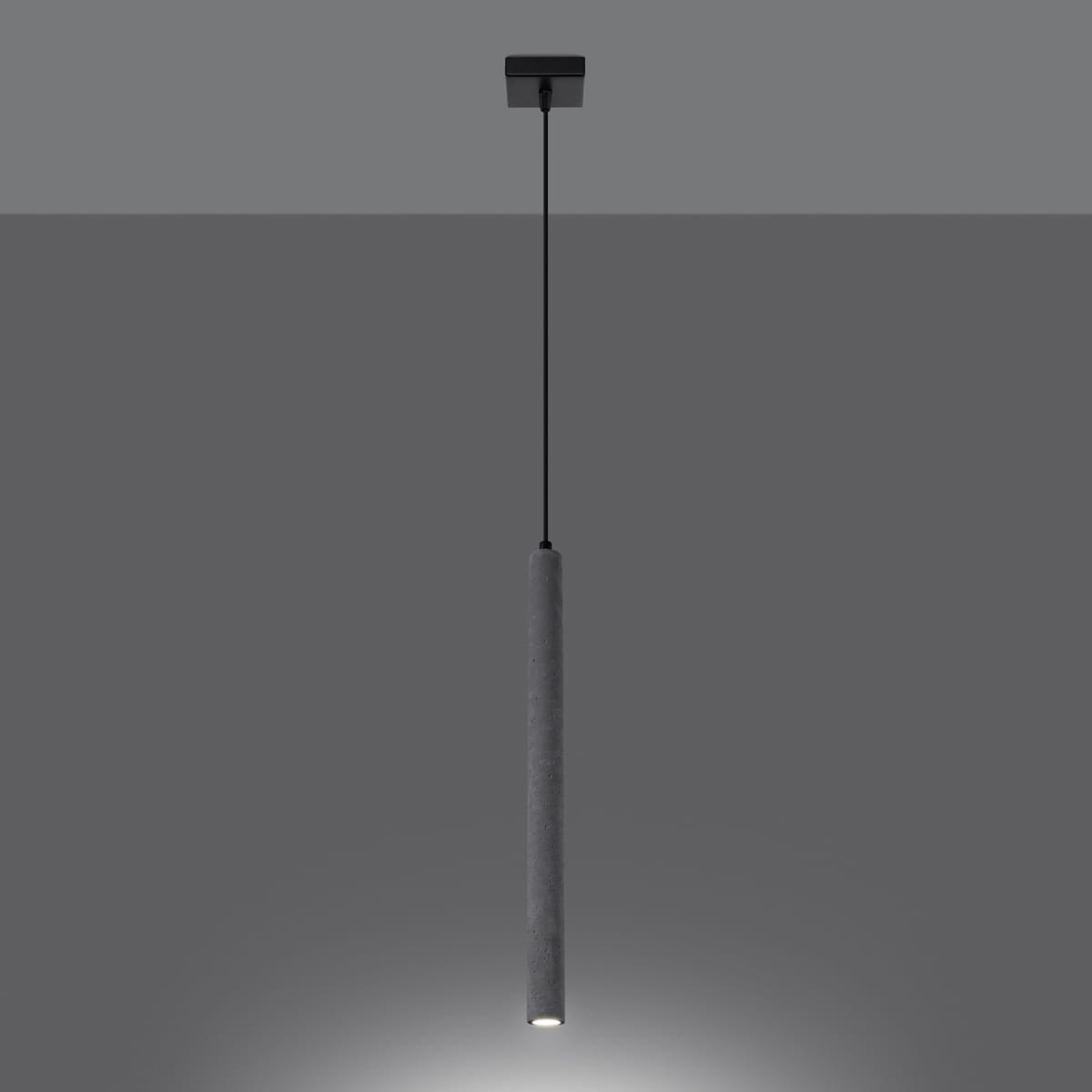 Lampa wisząca Pastelo 1xG9 w kolorze czarnym i betonowym. Prosty, cylindricalny kształt z betonu, zawieszona na czarnym przewodzie. Źródło światła umieszczone na dolnej końcówce. Tło w odcieniach szarości.