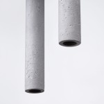 Lampa wisząca Pastelo z trzema oprawami G9, o cylindrycznych kloszach z betonu w odcieniu jasnoszarym. Klosze mają matową fakturę, zawieszone są na czarnym przewodzie. Tło proste, białe.