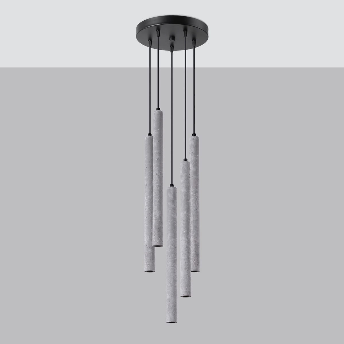 Lampa wisząca Pastelo z pięcioma cylindrycznymi kloszami w kolorze szarym z betonu, zawieszona na czarnych linkach, montowana do sufitu. Klosze różnej długości, minimalistyczny design, na szarym tle.