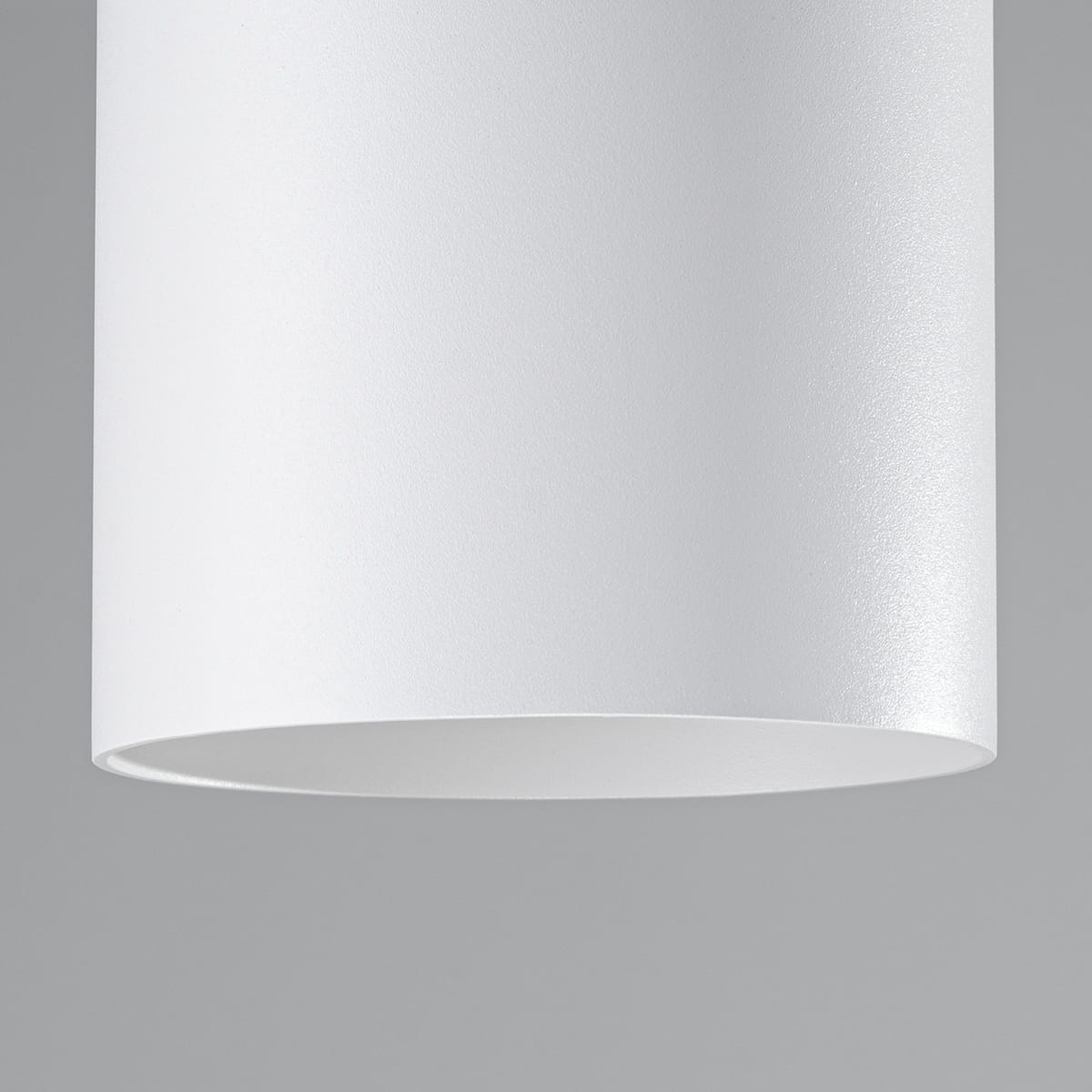Biała lampa sufitowa Mika z oprawą na 1 żarówkę GU10. Cylindryczny kształt z matowej powierzchni, widok z dołu, na szarym tle. Idealna do nowoczesnych wnętrz, minimalistyczny design.
