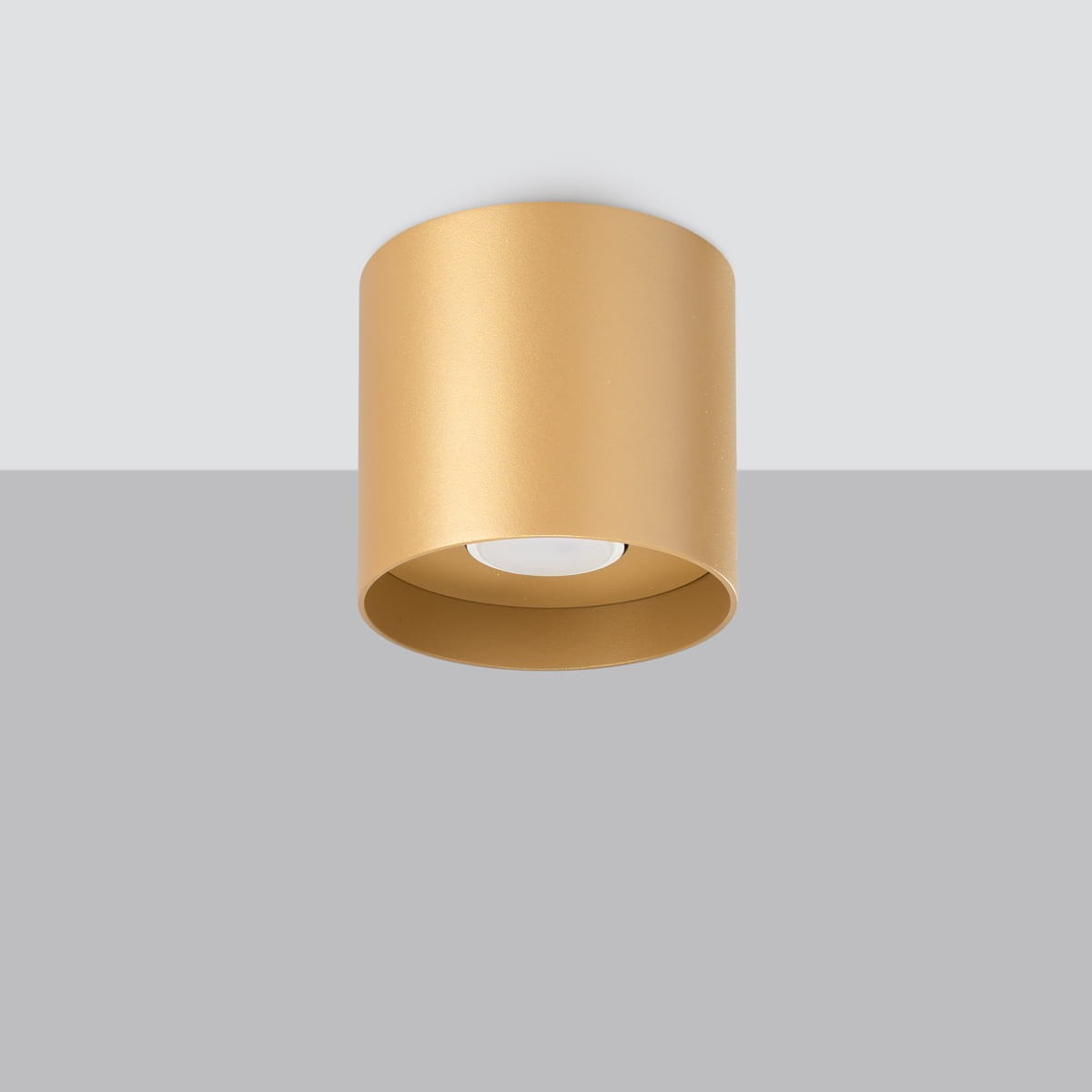 Lampa sufitowa Mika z jedną oprawą GU10, w złotym metalicznym kolorze. Okrągły kształt z matowym wykończeniem, zamontowana na szarym tle. Elementy oświetleniowe są widoczne wewnątrz lampy, co podkreśla nowoczesny design.