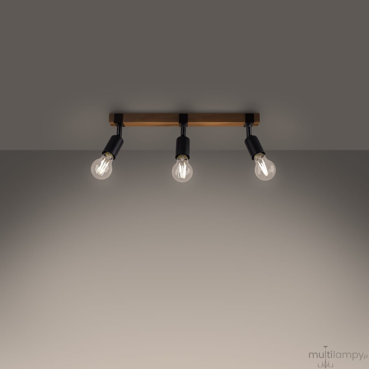 Lampa sufitowa Zuca z belką w jasnym drewnie i trzema oprawkami w kolorze czarnym, przeznaczona na żarówki E27. Ujęcie z góry, ukazujące równomierne rozmieszczenie źródeł światła na tle szarej ściany.