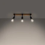 Lampa sufitowa Zuca z belką w jasnym drewnie i trzema oprawkami w kolorze czarnym, przeznaczona na żarówki E27. Ujęcie z góry, ukazujące równomierne rozmieszczenie źródeł światła na tle szarej ściany.