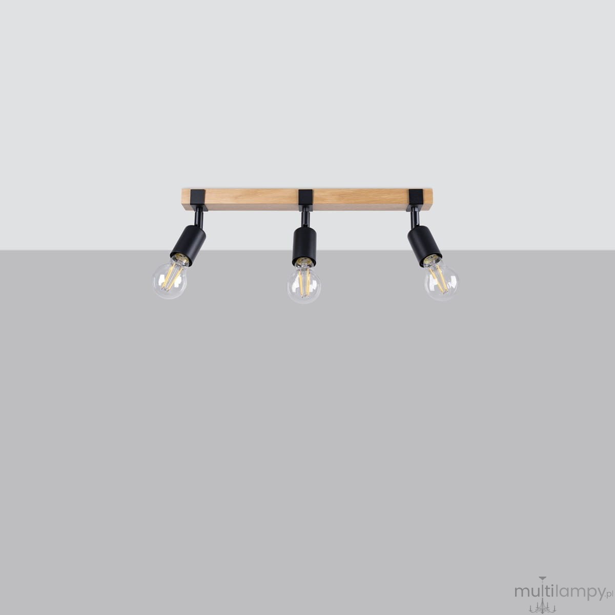 Lampa sufitowa Zuca z trzema oprawami E27, z drewnianym elementem w jasnym kolorze i czarnymi metalowymi uchwytami. Zamontowana poziomo, z widocznymi żarówkami w szklanych kloszach, na jednolitym szarym tle.