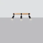Lampa sufitowa Zuca z trzema oprawami E27, z drewnianym elementem w jasnym kolorze i czarnymi metalowymi uchwytami. Zamontowana poziomo, z widocznymi żarówkami w szklanych kloszach, na jednolitym szarym tle.