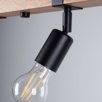 Czarna lampa sufitowa Zuca z miejscem na 4 żarówki E27, zamontowana pod drewnianym stropem. Widoczny detal uchwytu w kształcie cylindrycznym, z przezroczystą żarówką, podkreślającą nowoczesny styl oświetlenia. Tło w odcieniach szarości.