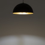 Lampa wisząca Hemisphere Hit D50 w kolorze czarnym z wewnętrzną złotą powłoką, zawieszona na cienkim kabelku. Kształt półkolisty, emitująca ciepłe światło, umieszczona w minimalistycznym otoczeniu.