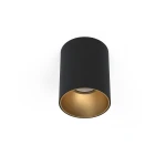 Lampa sufitowa Eye Tone 1-punktowa w kolorze czarnym z złotym wnętrzem. Ma cylindryczny kształt, zamontowana na suficie, z widocznym źródłem światła. Tło jest proste, co podkreśla elegancki design lampy.