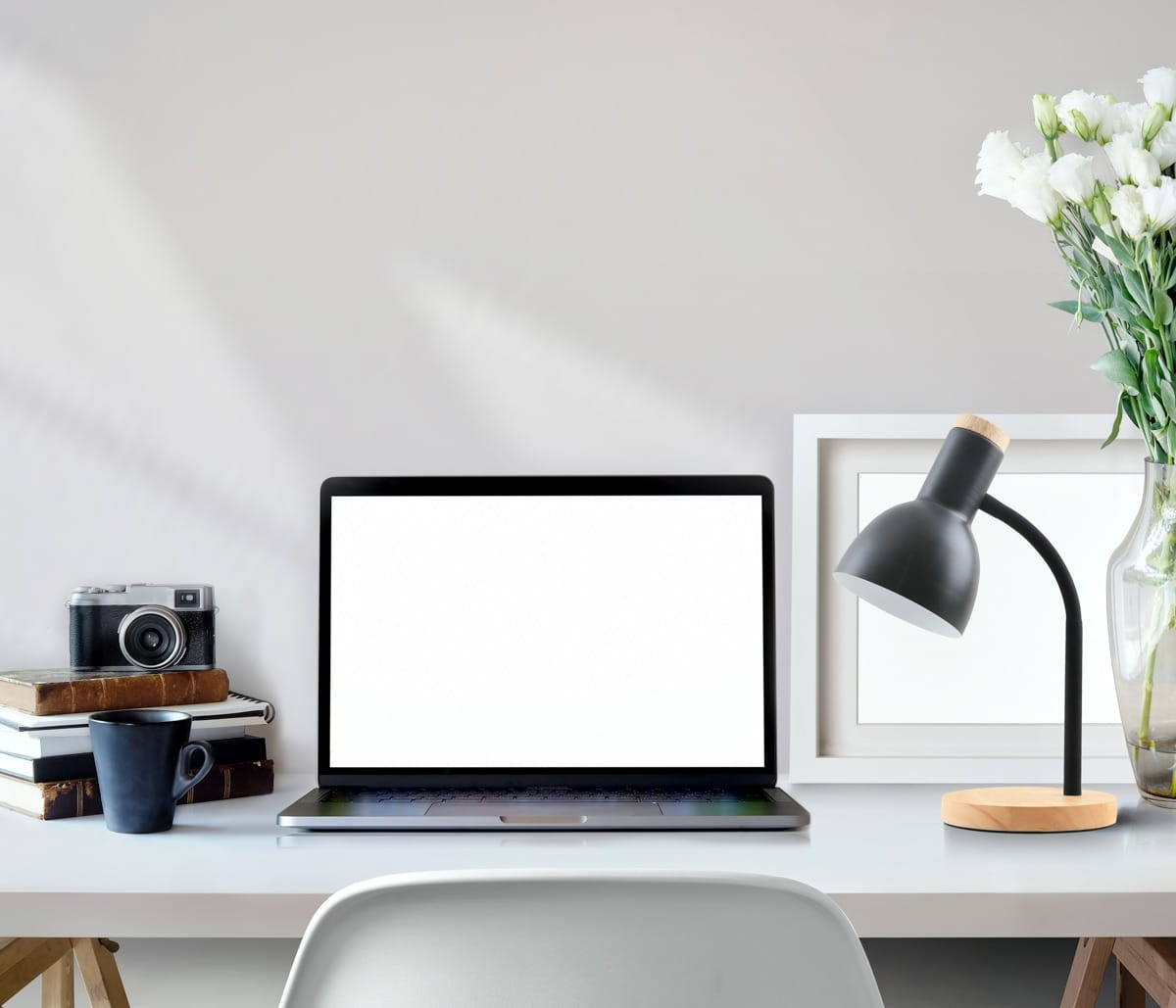 Lampka biurkowa Senza w kolorze czarnym z podstawą z naturalnego drewna. Posiada elastyczną szyjkę i oprawę na żarówkę E27. Ustawiona na biurku obok laptopa, filiżanki i książek, w tle z dekoracjami.