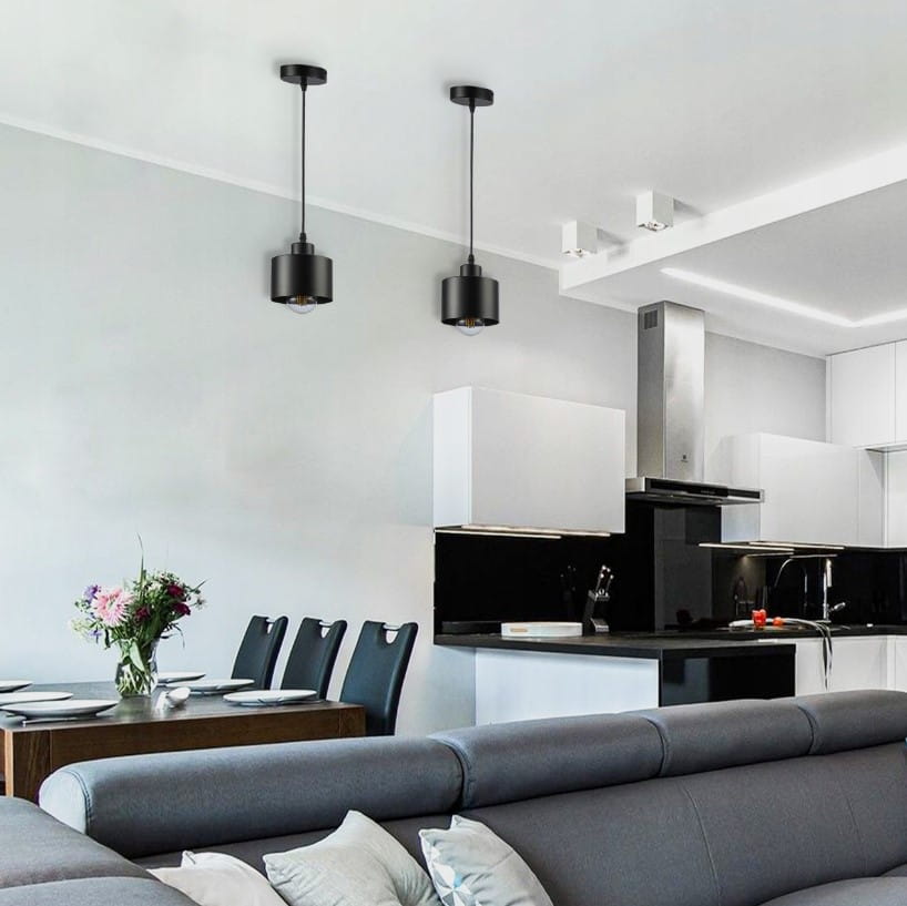 Lampa wisząca Elza 1xE27 w kolorze czarnym, zamontowana na suficie, z metalowym kloszem. Widoczna w nowoczesnym wnętrzu kuchni z białymi szafkami i drewnianym stołem, w otoczeniu kwiatów i talerzy.