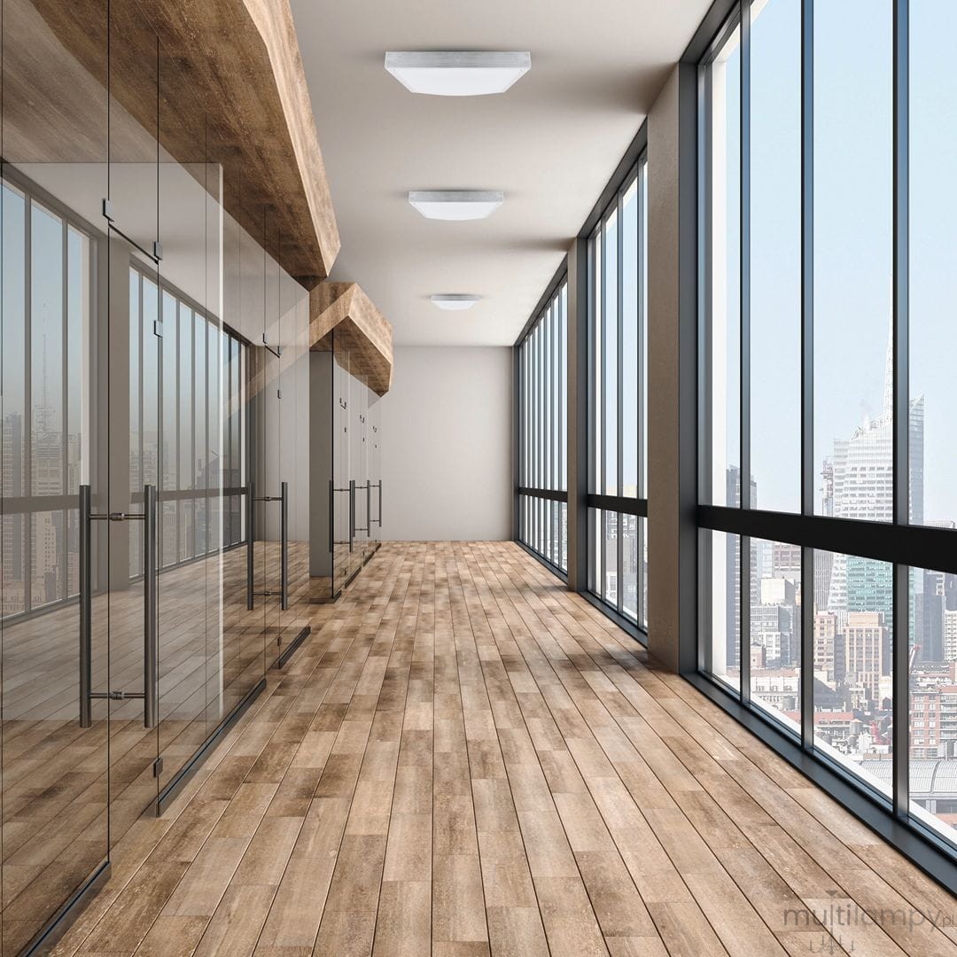 Plafon LED Casilla D50x50, 24W, 4000K, zamontowany na suficie w nowoczesnym wnętrzu. Widoczna drewniana podłoga, dużą szklaną ścianą z widokiem na miasto. Oświetlenie w kolorze białym, prostokątny kształt, elegancki design.