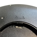 Plafon LED Maq D40, czarny, z widocznymi oznaczeniami UNLOCK i LOCK na metalowej powierzchni. Ujęcie w zbliżeniu, pokazujące detale mocowania. Matowa faktura i okrągły kształt.