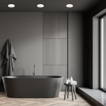 Plafon LED Vera D22 o mocy 18W, barwie 4000K, w białej obudowie, zamontowany w łazience. Oświetlenie sufitowe w minimalistycznym, nowoczesnym wnętrzu z ciemną wanną i szklanym oknem.