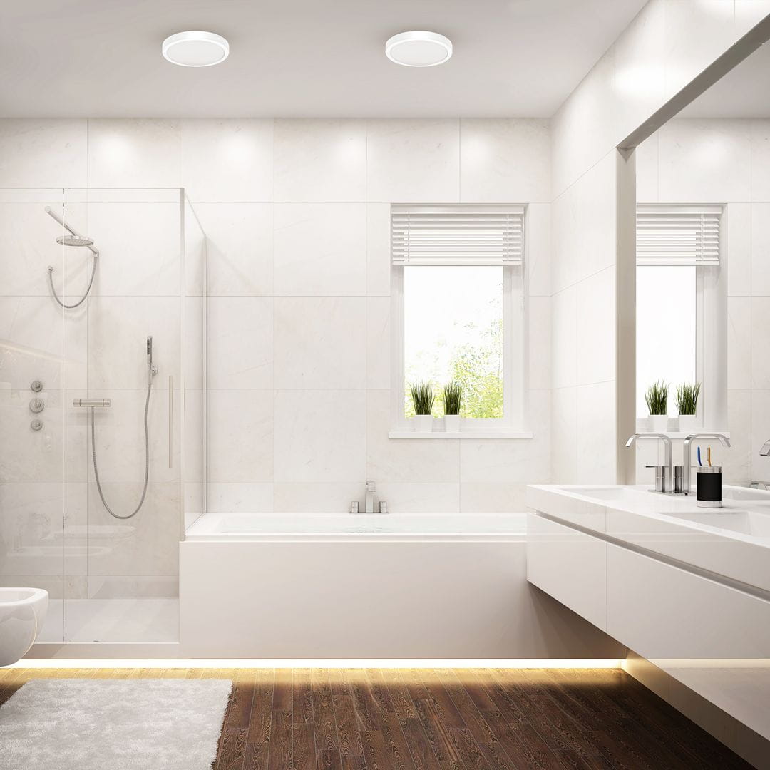 Plafon LED Vera D22 w kolorze białym, o mocy 18W i temperaturze barwowej 4000K, zamontowany na suficie w jasnej łazience z prysznicem i wanną. Oświetlenie w minimalistycznym stylu, zapewniające równomierne światło.