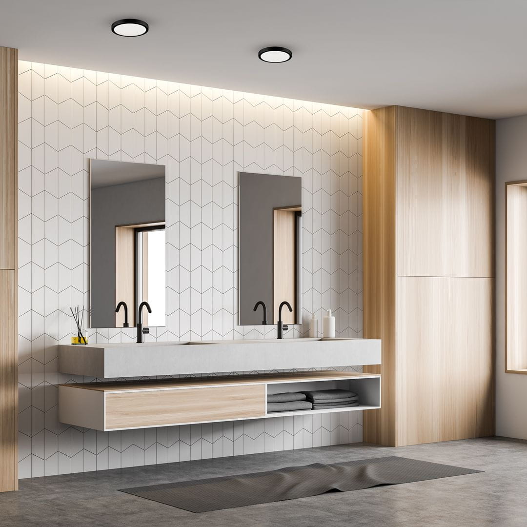 Plafon LED Vera D22 o mocy 18W i barwie 4000K w kolorze czarnym, zamontowany w nowoczesnej łazience. Widoczny w górnej części zdjęcia, otoczony jasnym, geometrycznym wzorem na ścianie oraz minimalistycznymi meblami.