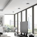 Plafon LED Marlon D18 w kolorze czarnym, o wymiarach 12W i 4000K, zamontowany w sufit, w zestawie z innymi lampami. W tle nowoczesny salon z dużymi oknami, telewizorem oraz meblami.