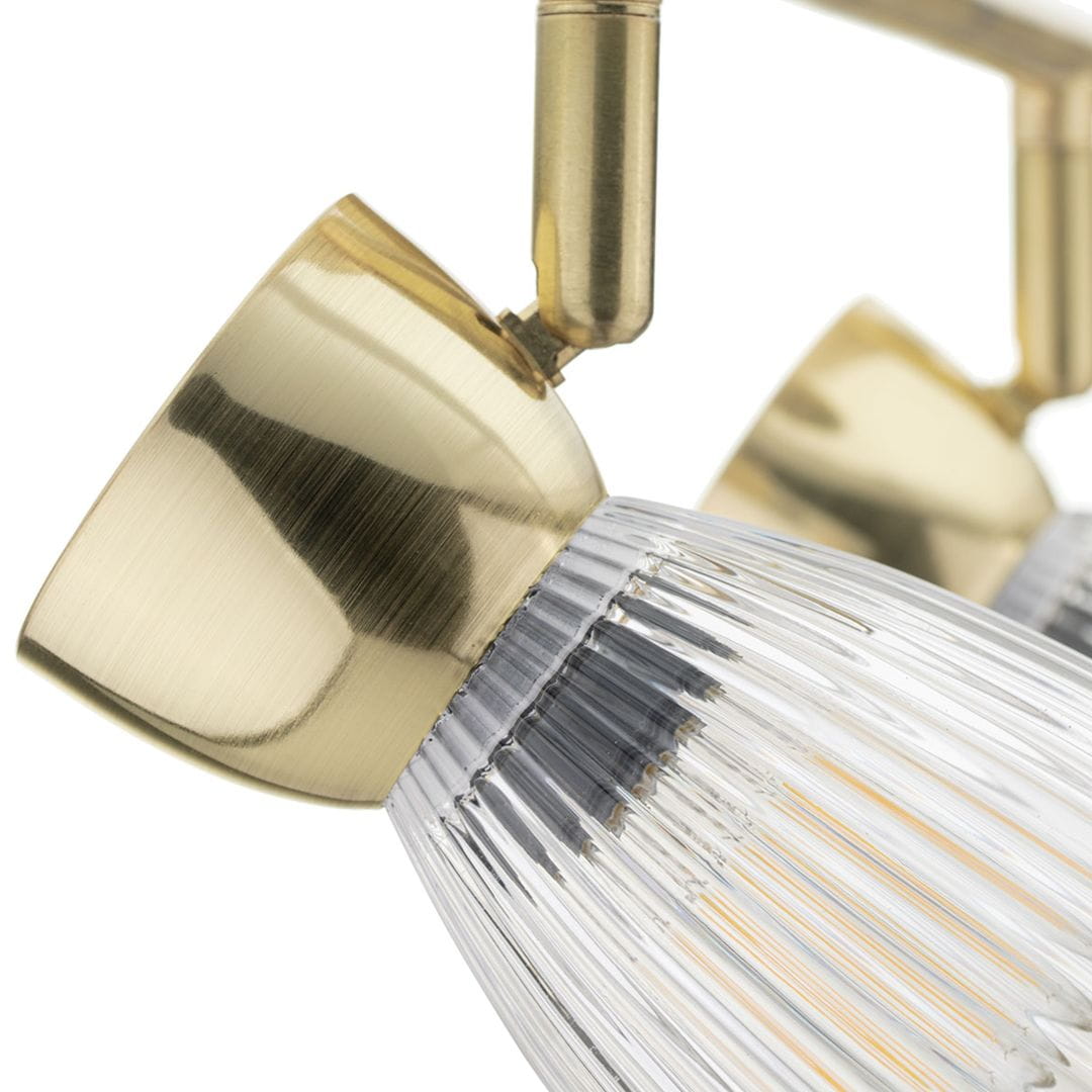 Złota lampa sufitowa typu spot z podwójnym źródłem światła E14. Widoczny detal szklanej klosza z wgłębieniami oraz metalowa, błyszcząca oprawa. Ujęcie z boku, ukazujące mechanizm regulacji kąta.