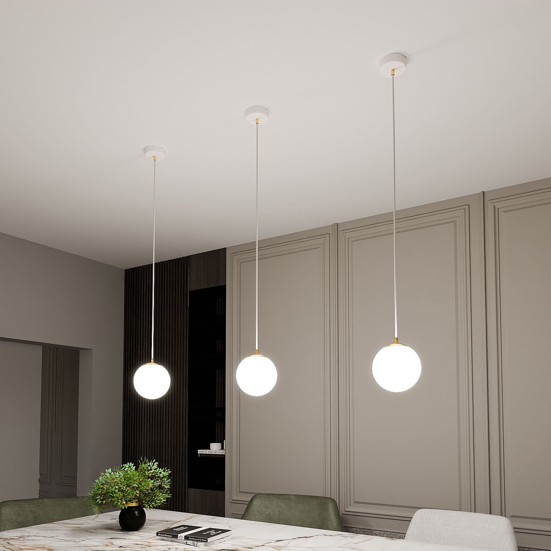 Lampa wisząca Royal 1-punktowa w kolorze białym i złotym, z okrągłym kloszem. Zawieszona na cienkim kablu, w nowoczesnym wnętrzu z jasnymi ścianami i stołem. W tle widoczna roślinność oraz elementy mebli.