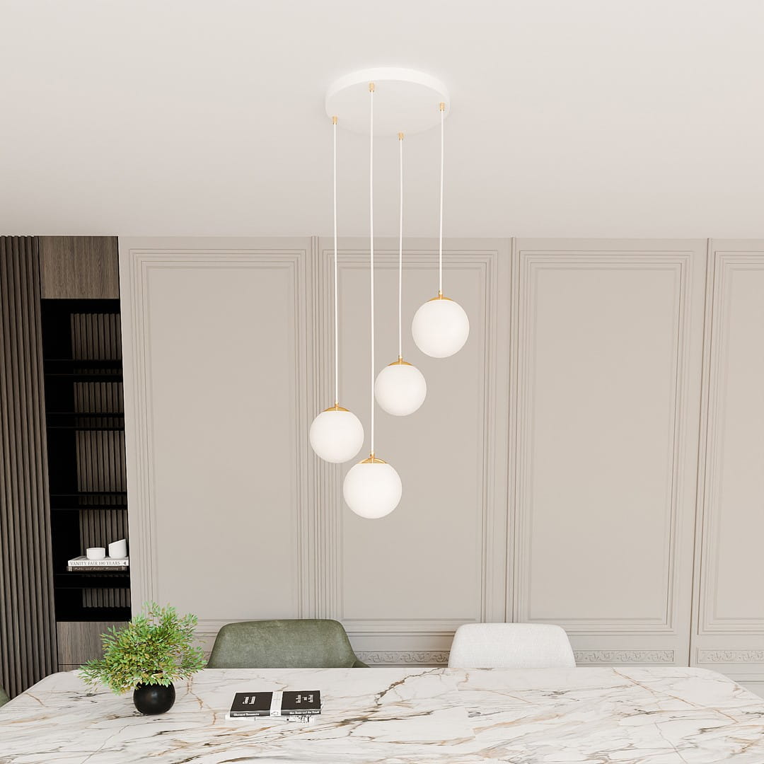Lampa wisząca Royal 4-punktowa w kolorze białym i złotym, zawieszona na długich linkach. Cztery okrągłe klosze z matowego szkła z złotymi detalami, umieszczone na białym stropie, nad marmurowym stołem. Tło w neutralnych odcieniach.