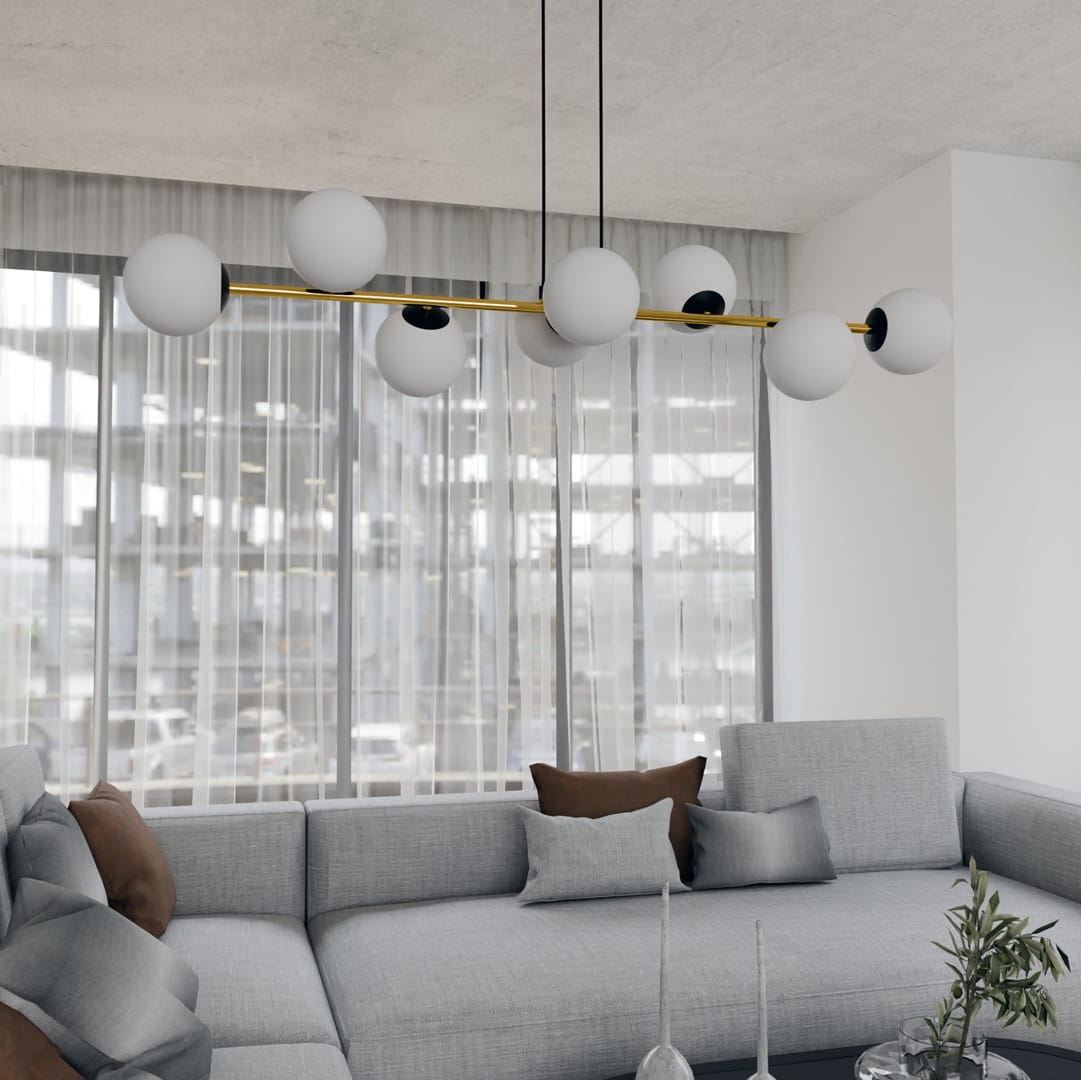 Lampa wisząca Gravity 8-punktowa w kolorze czarnym i złotym, z białymi kulami, umieszczona nad szarym narożnikiem. Wisi na dwóch czarnych linkach, w nowoczesnym wnętrzu z dużymi oknami i zasłonami.