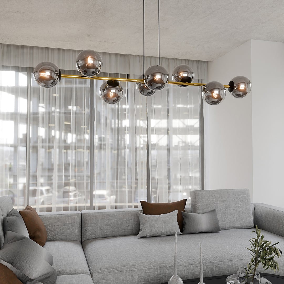 Lampa wisząca Gravity 8-punktowa w kolorze czarnym, złotym i grafitowym. Posiada osiem okrągłych, metalicznych kloszy na cienkiej, złotej listwie. Zawieszona na dwóch czarnych linkach, umiejscowiona nad szaro-beżową sofą we wnętrzu z dużymi oknami.