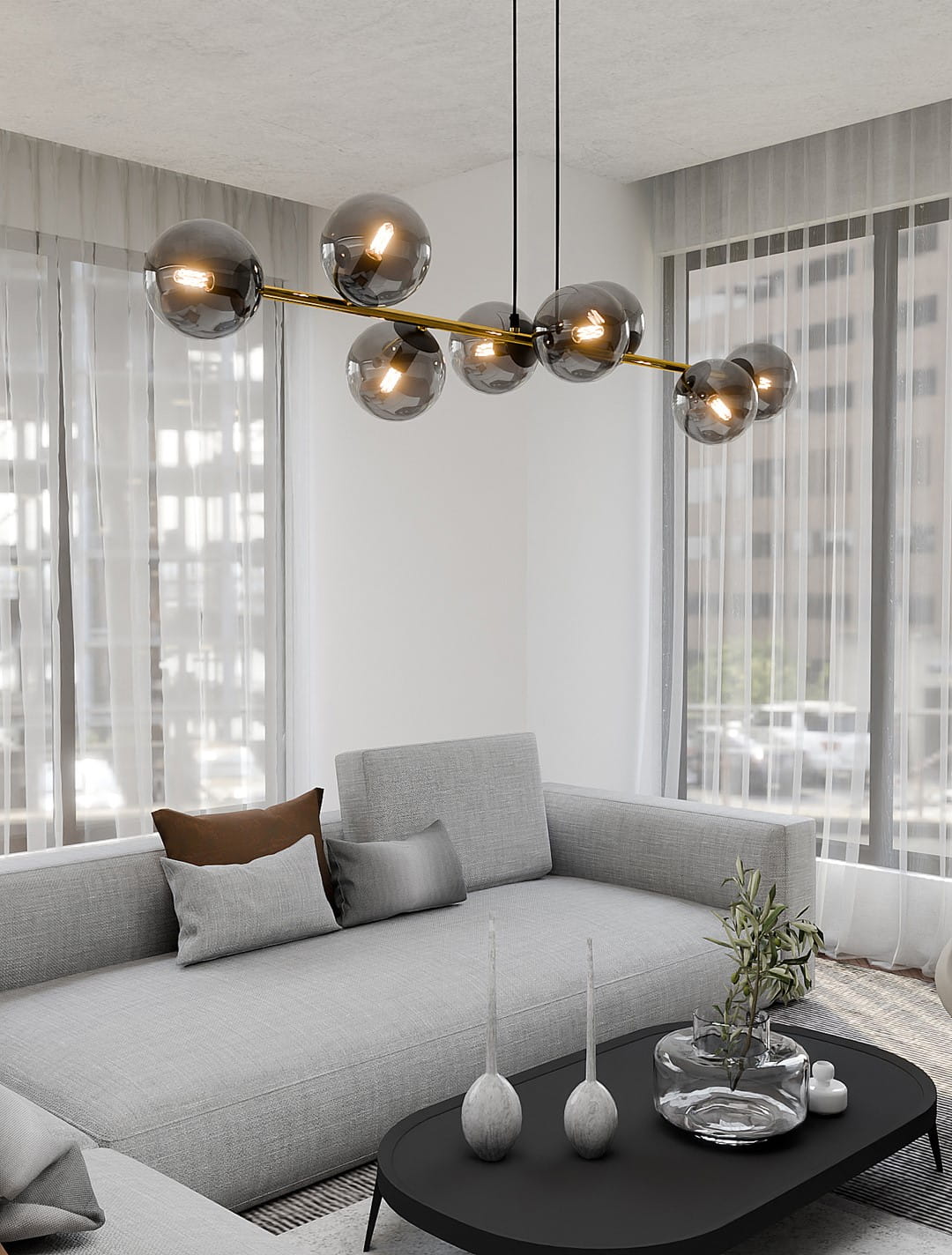 Lampa wisząca Gravity 8-punktowa w kolorze czarnym, złotym i grafitowym, z sześcioma szklanymi kloszami w odcieniu grafitowym, zawieszona na długich czarnych linkach. Umieszczona nad szarym narożnikiem w nowoczesnym wnętrzu.