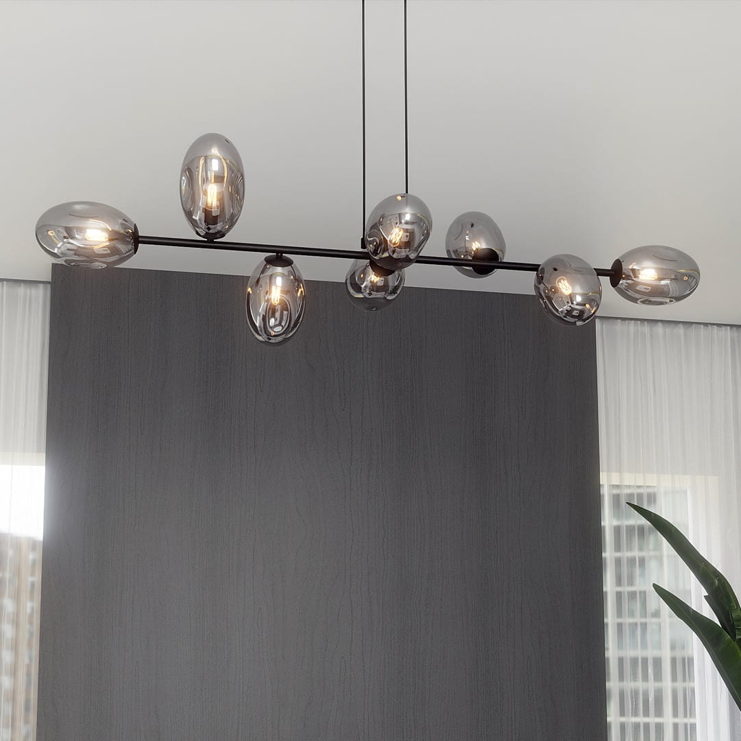 Lampa wisząca Pandora 8-punktowa w kolorze czarnym i grafitowym, z ośmioma szklanymi kloszami w kształcie jajek. Ułożona na prostym metalowym stelażu, wisi pod kątem, tworząc nowoczesną aranżację w przestrzeni. Tło w odcieniach szarości.