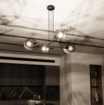 Lampa wisząca Playa 4-punktowa w kolorze czarnym, posiadająca cztery klosze w kształcie muszli z metalową teksturą. Ujęcie z dołu, montowana na suficie, w nowoczesnym wnętrzu kuchennym. Dobrze widoczne cienie na suficie.