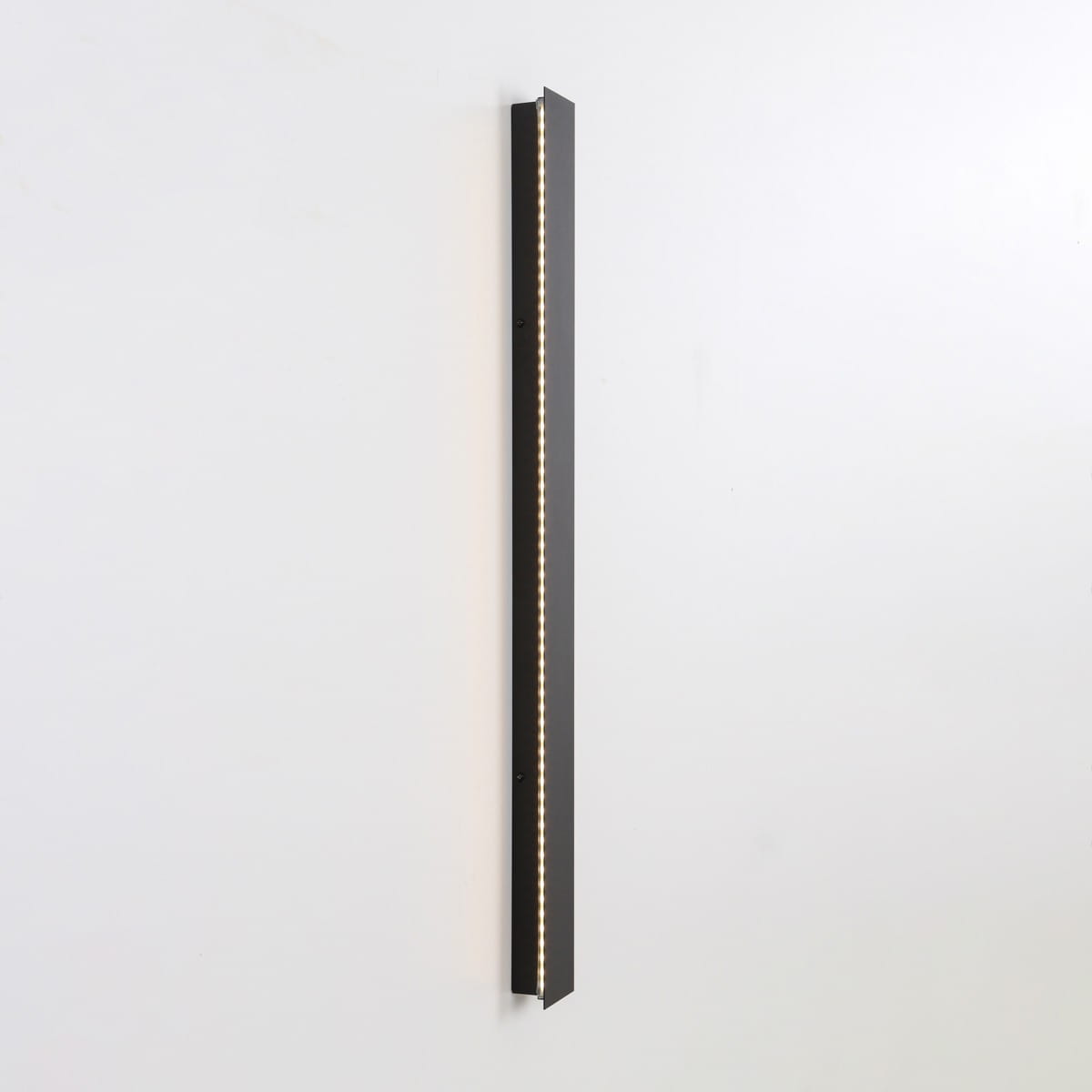 Kinkiet zewnętrzny Mutti 4K w kolorze czarnym, o długości pionowej, z wbudowanym oświetleniem LED (6x14W, 4000K). Produkt zamontowany na białej ścianie, podświetlający przestrzeń dzięki cienkiemu, minimalistycznemu designowi.