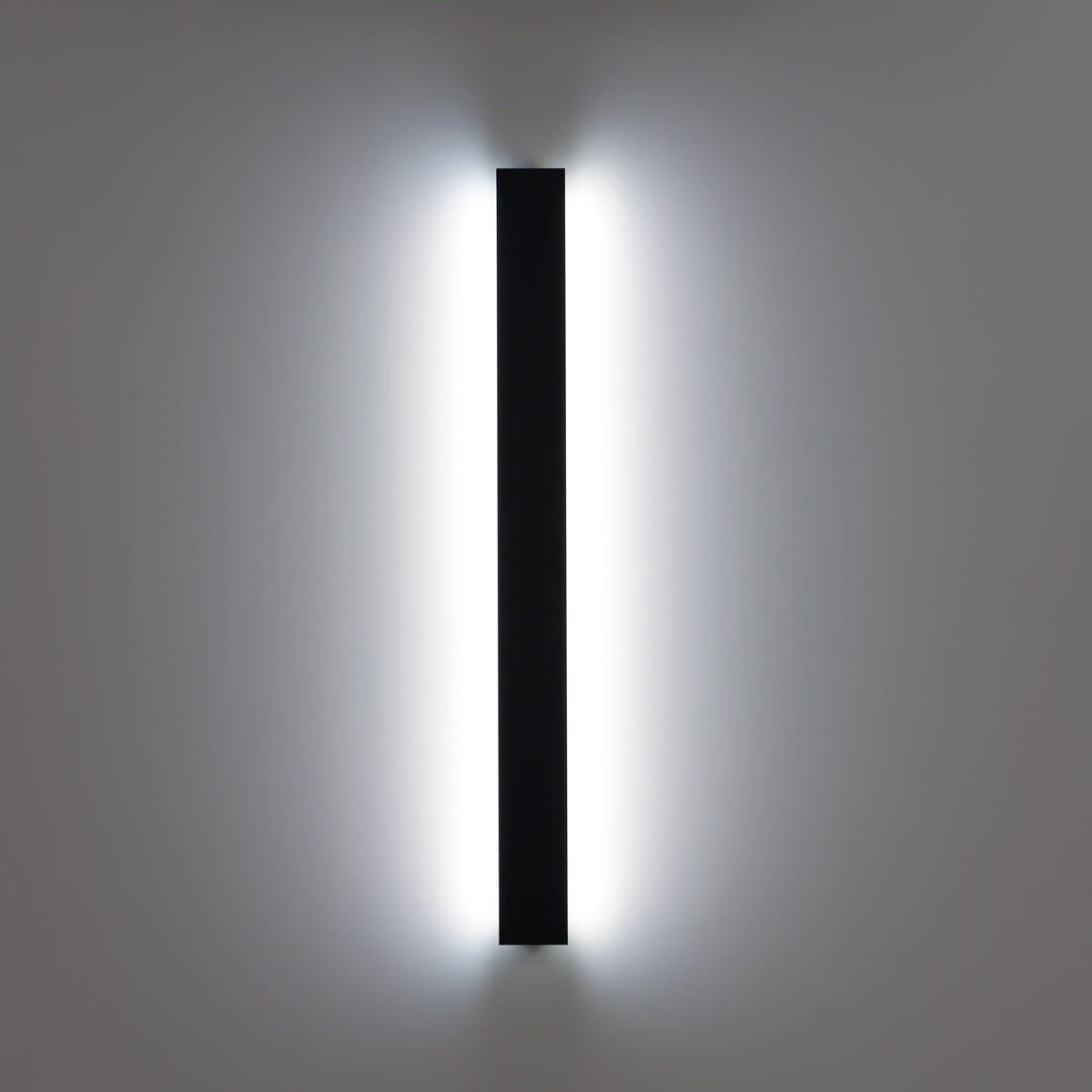 Kinkiet zewnętrzny Mutti 4K w kolorze czarnym, z 12 diodami LED o mocy 29W i temperaturze barwowej 4000K. Prosty, prostokątny kształt montowany pionowo, emitujący światło z obu stron, na gładkiej, jasnej ścianie.