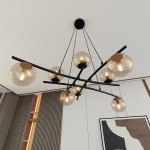 Lampa wisząca Essa 8-punktowa w kolorze czarnym i miodowym, z ośmioma przezroczystymi kulami ze szkła, zawieszona na cienkich linkach. Kule osadzone na czarnych prętach, prezentujące nowoczesny design, w tle minimalistyczne wnętrze.