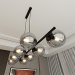 Lampa wisząca Rory 8-punktowa w kolorze czarnym i grafitowym, z przezroczystymi kulami, zawieszona na prostokątnej podstawie. Kule z żarówkami widoczne w różnych pozycjach, zawieszone na cienkich linkach. Tło jasne, z elementami dekoracyjnymi.