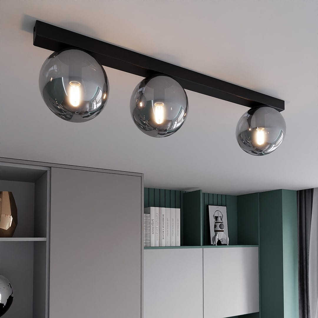 Fit lampa sufitowa 3-punktowa w kolorze czarnym i grafitowym, z trzema okrągłymi kloszami w odcieniu szaro-srebrnym. Zawieszona poziomo pod sufitem w nowoczesnym wnętrzu, na tle szafek w odcieniach szarości i zieleni.