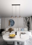 Lampa wisząca Cosmo 3-punktowa w kolorze grafitowym, z trzema przezroczystymi kloszami w kształcie kul, zawieszona na czarnych linkach. Ujęcie frontalne, lampa umieszczona nad stołem w nowoczesnym wnętrzu.