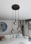 Grafitowa lampa wisząca Cosmo Premium z trzema szklanymi kulami, zawieszona na czarnych linkach. Kule mają transparentne dno, a w każdej znajduje się żarówka. Lampa zamontowana na okrągłym, czarnym stelażu, umieszczona w nowoczesnym wnętrzu z jasną sofą.