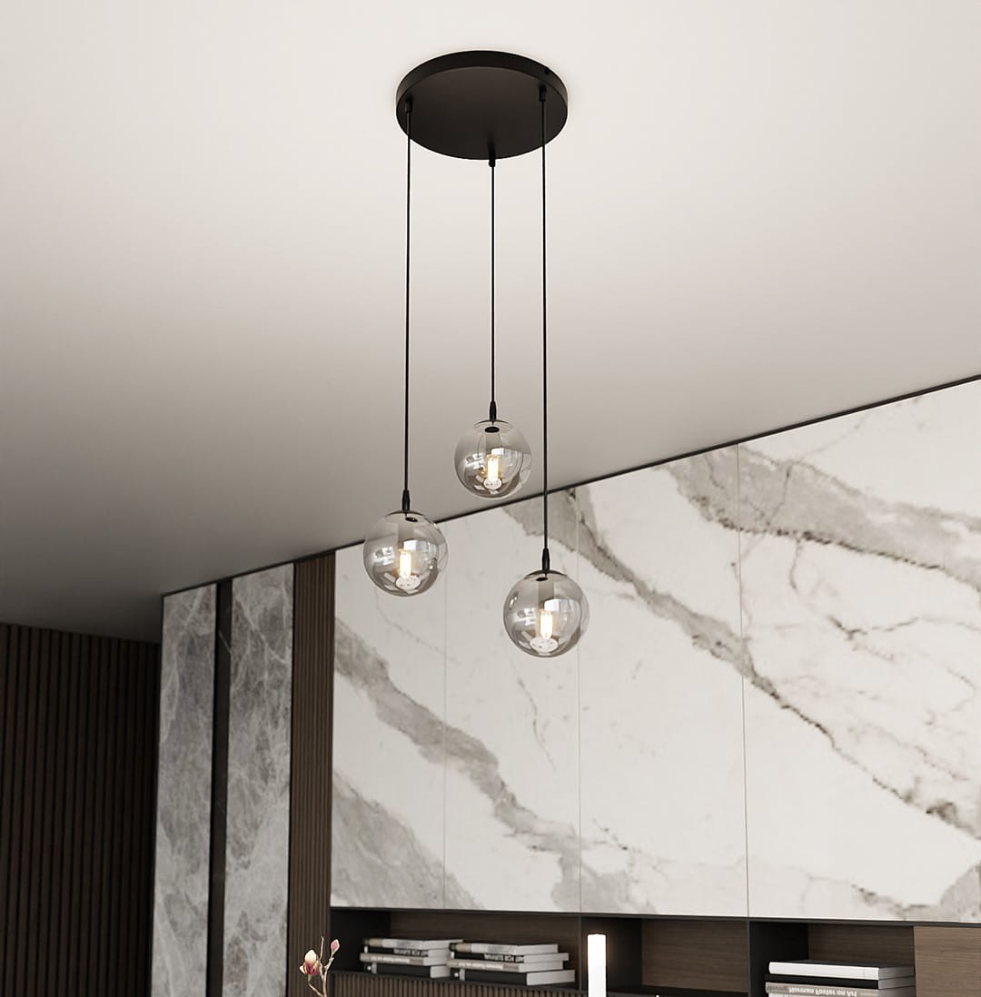Lampa wisząca Cosmo Premium 3-punktowa w kolorze grafitowym z trzema przezroczystymi kloszami. Zawieszona z sufitu, na długich linkach, w nowoczesnym wnętrzu z marmurowymi akcentami.