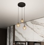 Lampa wisząca Cosmo Premium 3-punktowa w kolorze miodowym z trzema szklanymi kulami zawieszonymi na czarnych linkach, montowana na okrągłej podsufitce. Tło w odcieniach białych i szarych, z marmurowym wzorem.