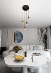 Lampa wisząca Cosmo Premium 4-punktowa w kolorze miodowym, z czterema okrągłymi kloszami w przezroczystym szkłach, zawieszona na czarnych linkach z sufitu. Umieszczona w nowoczesnym wnętrzu, nad okrągłym białym stołem.