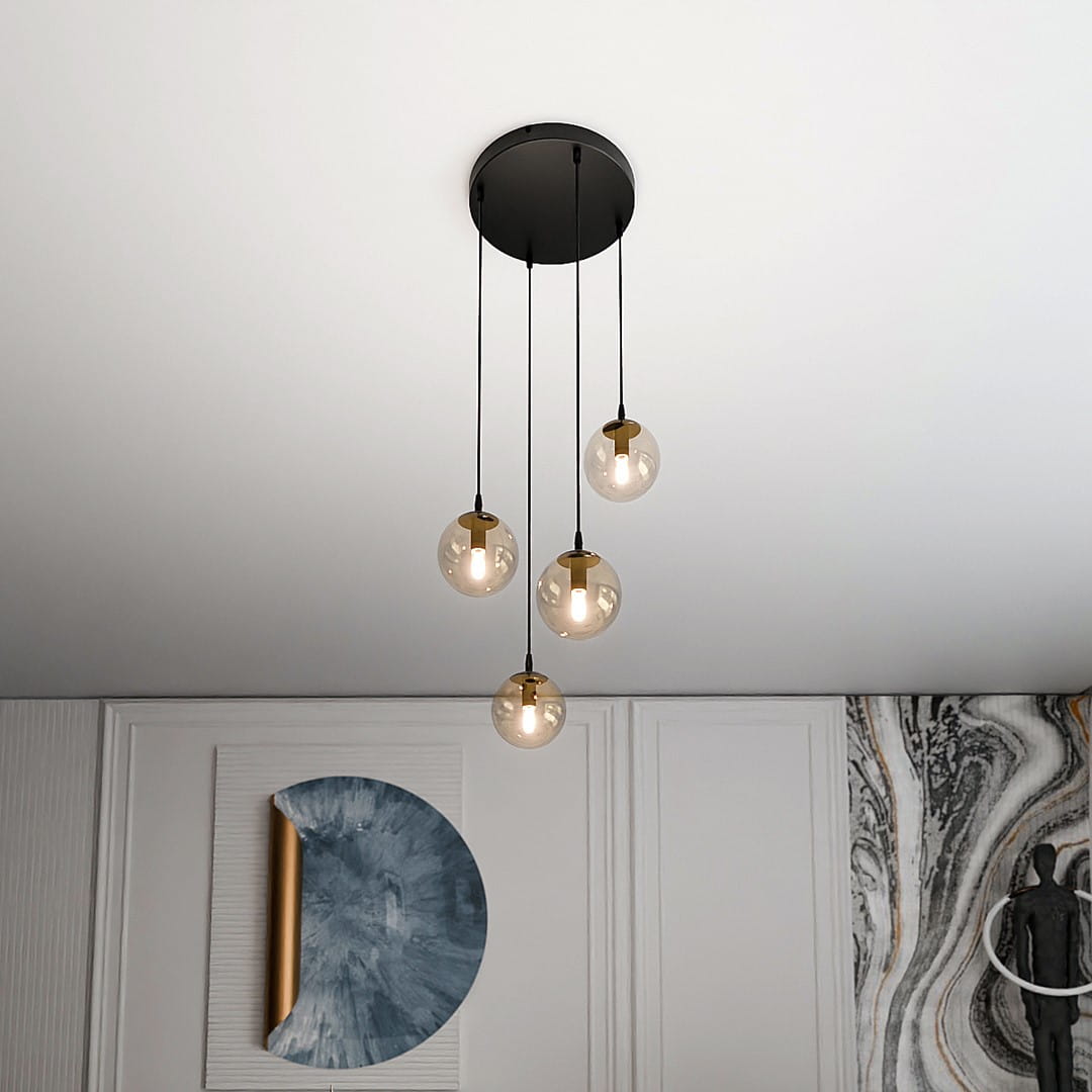 Czarna lampa wisząca Cosmo Premium z czterema szklanymi kloszami w miodowym odcieniu, zawieszona na długich linkach. Produkt umieszczony w nowoczesnym wnętrzu, z białym sufitem i dekoracyjną ścianą w tle.