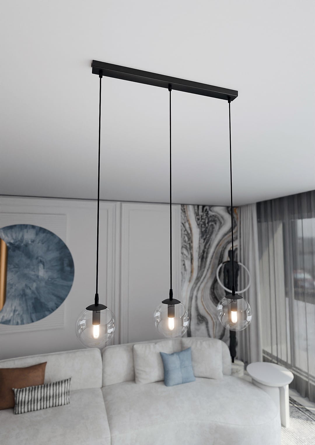 Lampa wisząca Cosmo 3-punktowa z przezroczystymi kloszami, zawieszona na czarnym stelażu. Widok z góry na trzy okrągłe klosze, każdy z żarówką, zawieszone na cienkich linkach. Tło jasne, minimalistyczne wnętrze z sofą i dekoracjami.