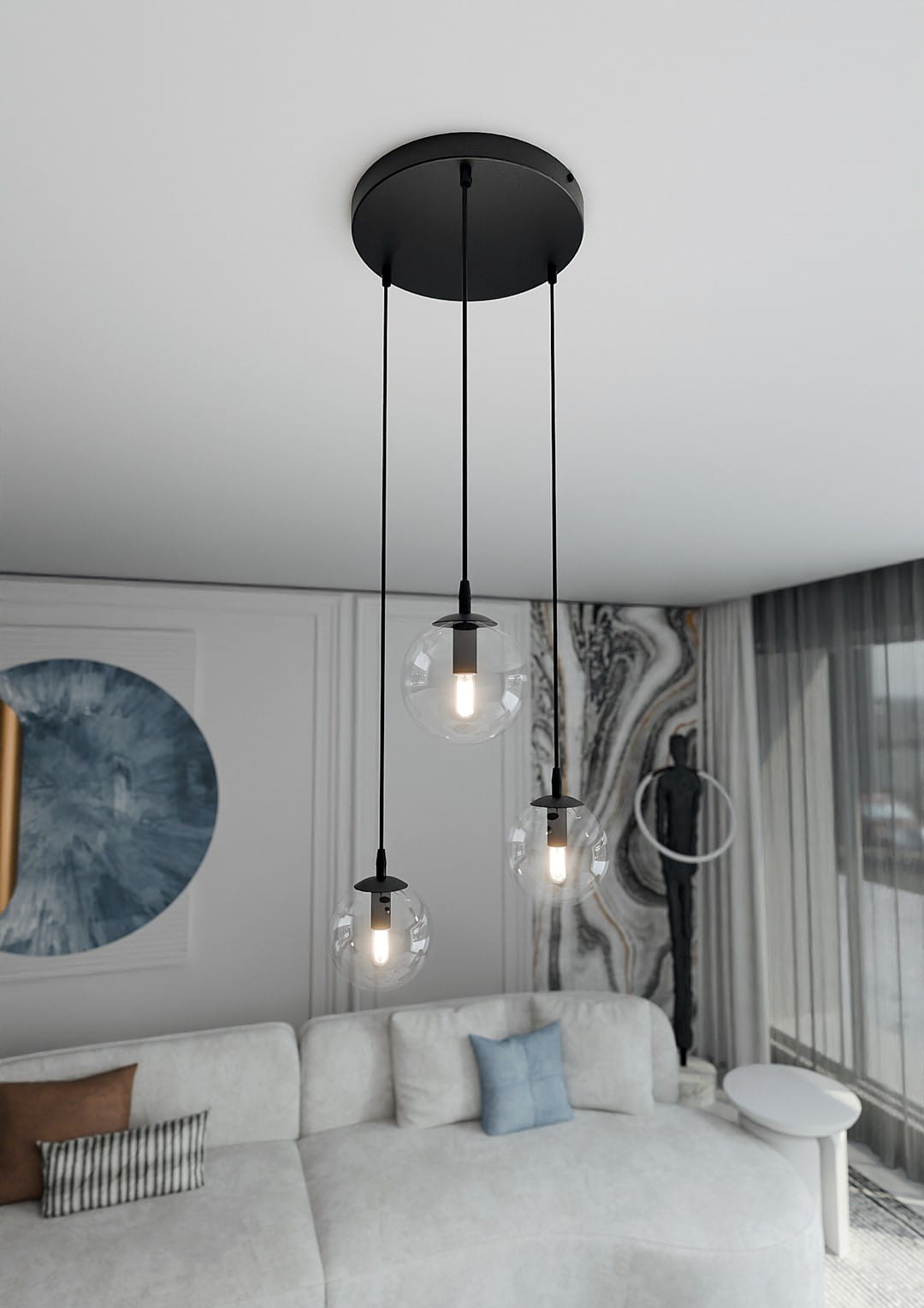 Lampa wisząca Cosmo Premium 3-punktowa z transparentnymi kloszami, zawieszona na czarnych linkach. Klosze mają okrągły kształt, a wewnątrz znajdują się żarówki. Produkt umieszczony w nowoczesnym wnętrzu z jasną sofą i dekoracjami.