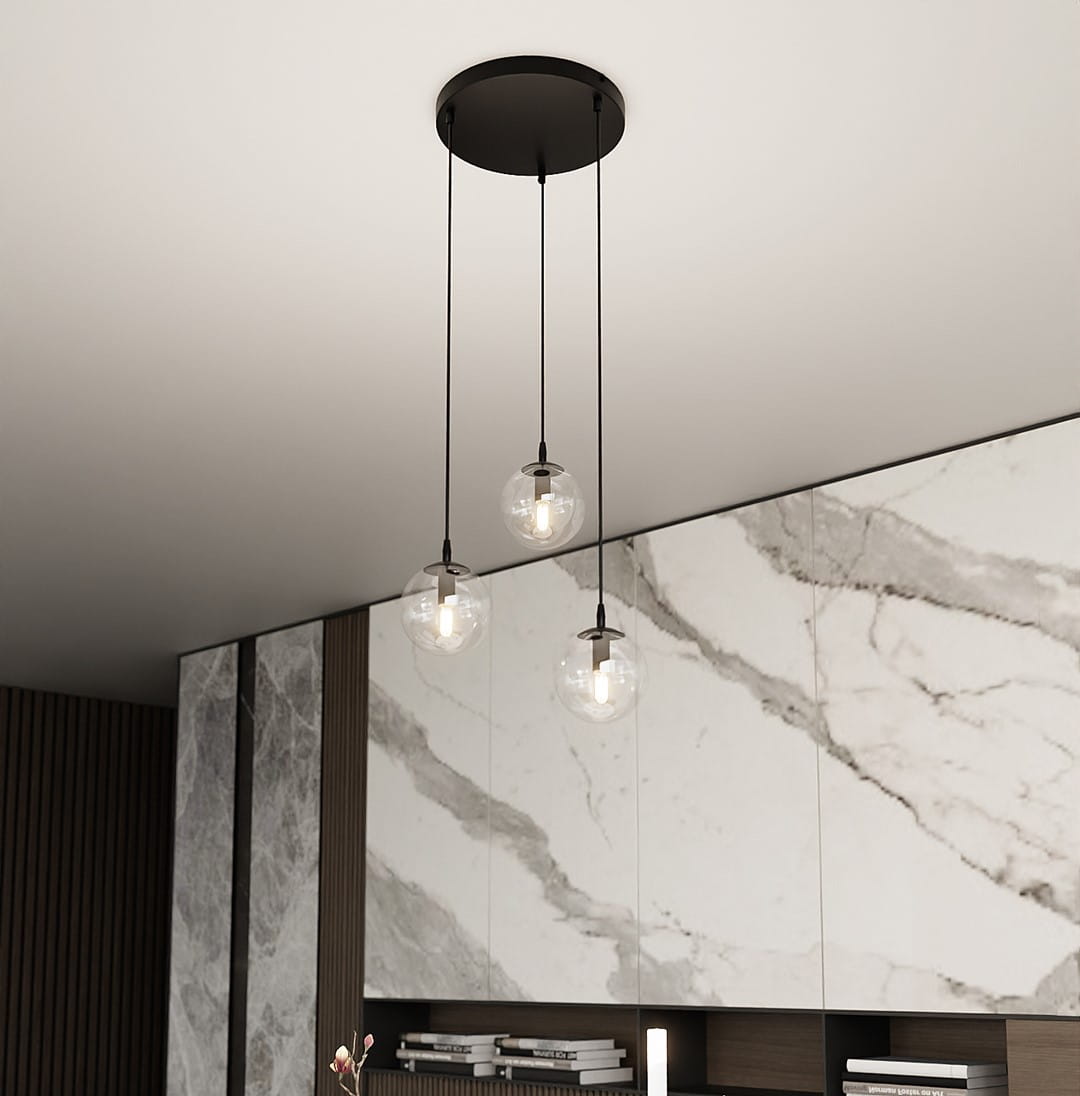 Lampa wisząca Cosmo Premium 3-punktowa z przezroczystymi kulistymi kloszami, zawieszona na czarnych linkach. Montowana do sufitu, w otoczeniu nowoczesnej aranżacji z marmurowymi i drewnianymi elementami.