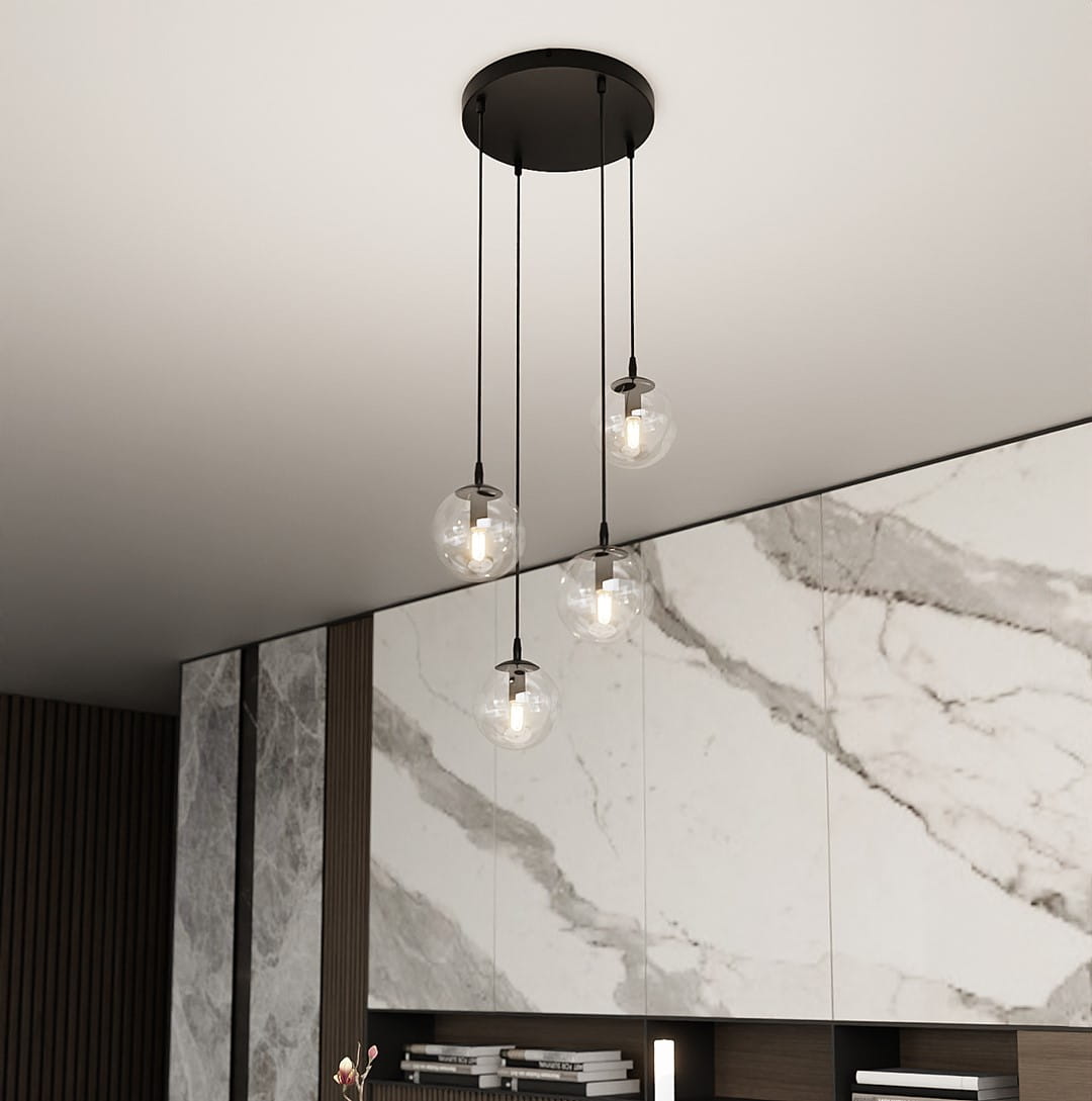 Lampa wisząca Cosmo Premium 4-punktowa z przezroczystymi kloszami, zawieszona na czarnych linkach. Klosze w kształcie kul, emitujące światło, umieszczone na okrągłej podstawie sufitowej. Tło w odcieniach szarości z marmurowymi i drewnianymi elementami.