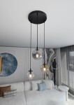 Lampa wisząca Cosmo Premium 3-punktowa w kolorze multikolorowym, składająca się z trzech przezroczystych kul w różnych odcieniach, zawieszona na czarnych linkach. Zainstalowana pod sufitem, w nowoczesnym wnętrzu z jasną sofą i dekoracjami.