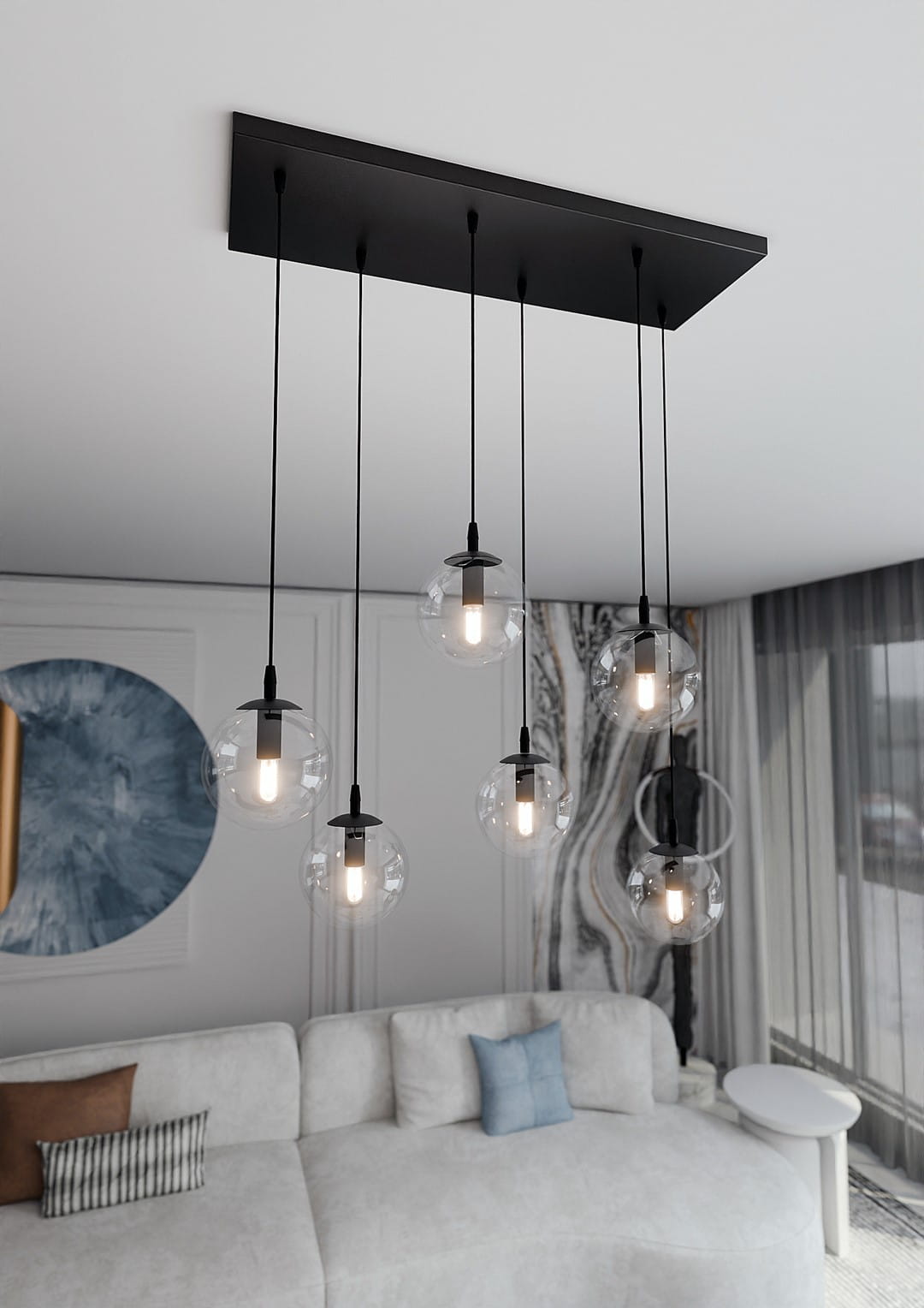 Lampa wisząca Cosmo 6-punktowa z transparentnymi kulami, zawieszona na czarnych przewodach. Kuliste klosze zapewniają nowoczesny design, a całość umieszczona jest na prostokątnej podstawie. Widoczna aranżacja w jasnym wnętrzu z sofą i dekoracjami.