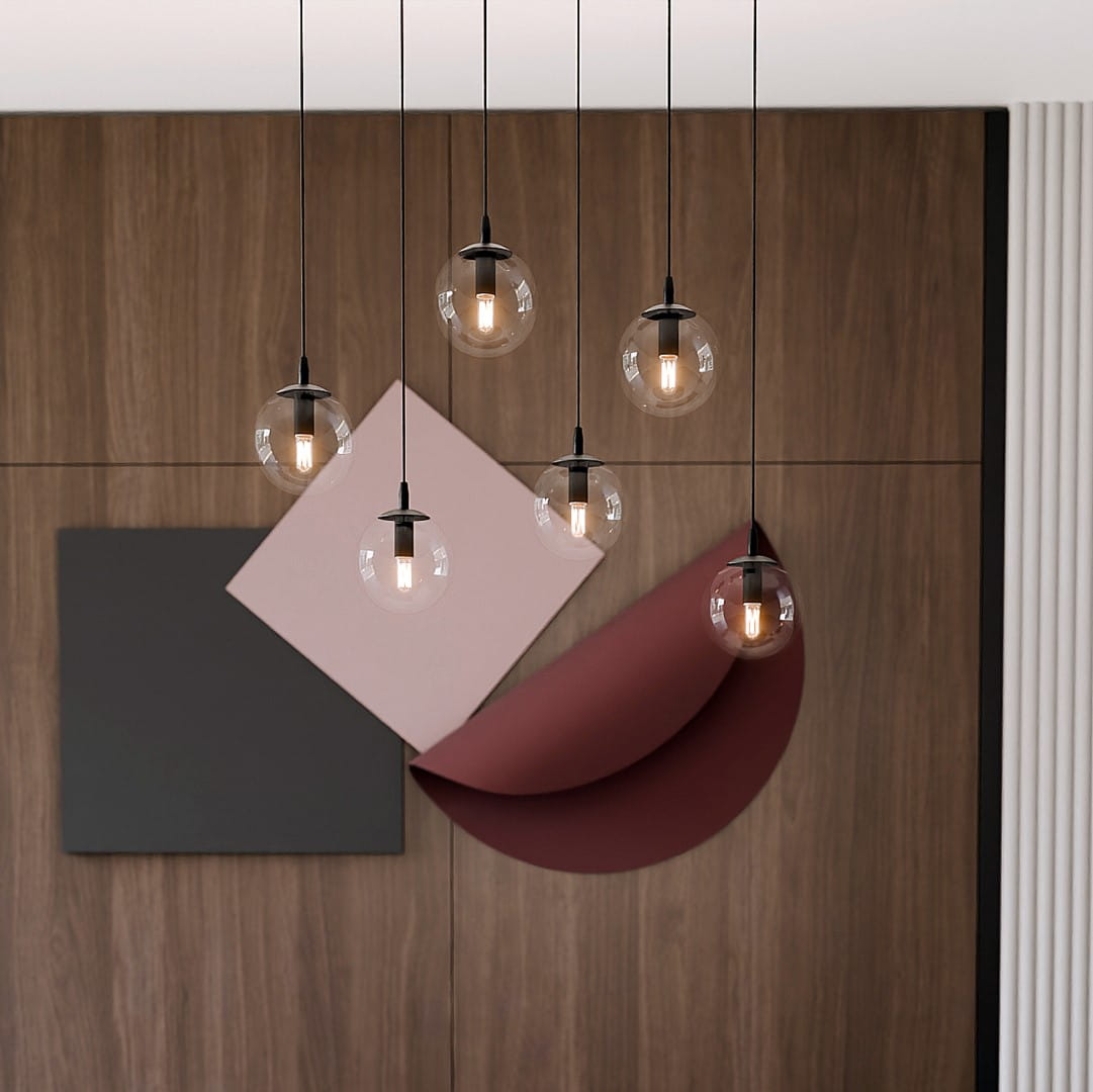 Lampa wisząca Cosmo 6-punktowa z przezroczystymi kloszami w kształcie kul, zawieszona na czarnych linkach. Tło z drewnianej ściany oraz geometryczne elementy w odcieniach różu i burgunda.