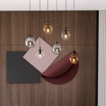 Lampa wisząca Cosmo mix 1 lampa wisząca 6-punktowa, z sześcioma kulistymi kloszami w odcieniach złota, srebra i przezroczystego szkła, zawieszona na czarnych przewodach. Tło w odcieniach drewna z geometrycznymi elementami dekoracyjnymi.