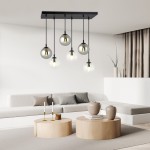 Lampa wisząca Cosmo mix2, 6-punktowa, z sześcioma przezroczystymi kulami na czarnych kablach, zamontowana na prostokątnej podstawie. Produkt wiszący nad okrągłymi stolikami w nowoczesnym wnętrzu.