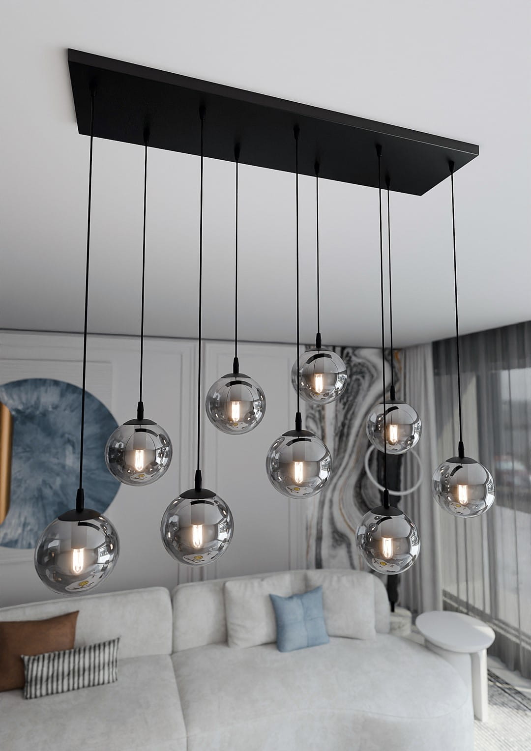 Lampa wisząca Cosmo 9-punktowa w kolorze grafitowym, z dziewięcioma przezroczystymi kulistymi kloszami zawieszonymi na cienkich czarnych linkach. Ujęcie z góry, prezentujące lampę nad białą sofą w nowoczesnym wnętrzu.